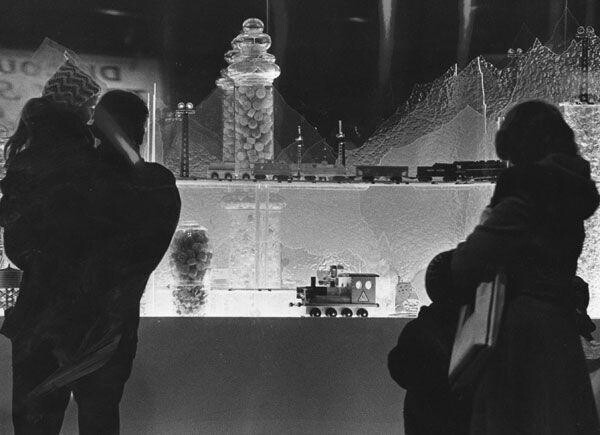 Shoppers looking in the window at a Christmas display; December 18, 1974