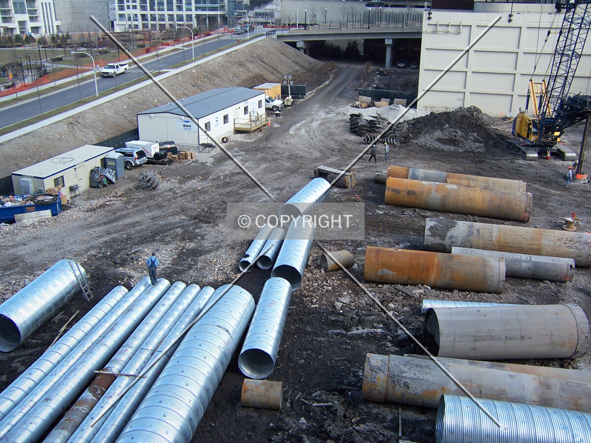 Caisson tubes and tops on the site. The tubes on the left will be lifted into the holes and filled with rebar and concrete