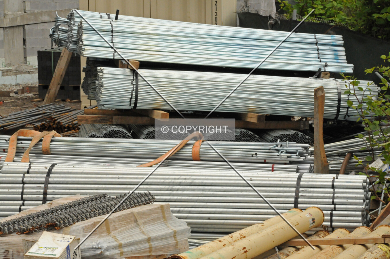 Bundles of electrical conduit in the staging area between the building and the adjacent railroad tracks