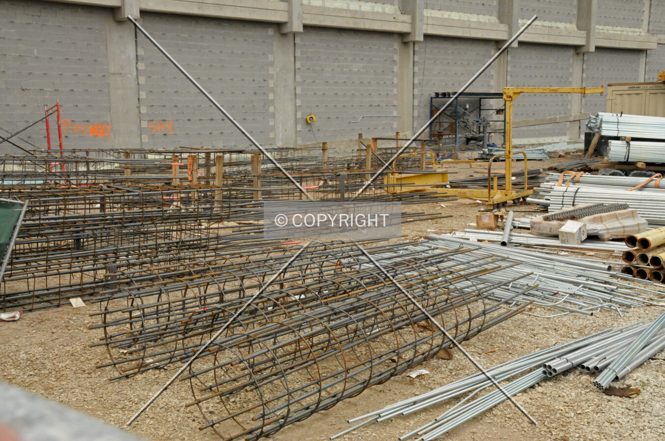 Assembled rebar cages and electrical conduit staged to the east of the building