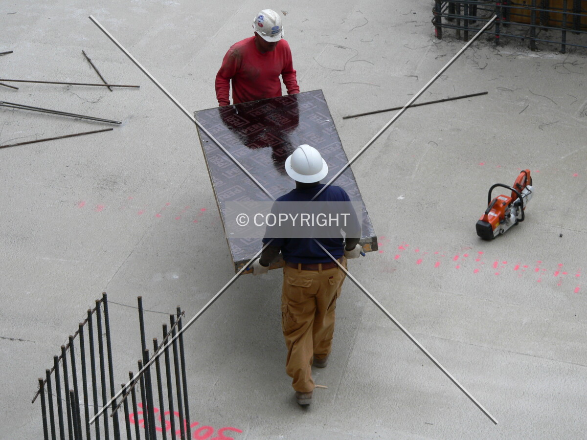 Construction workers carrying a piece of formwork
