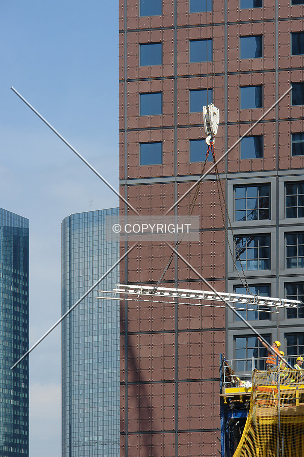 A ladder is brought to the construction site and received by a construction worker