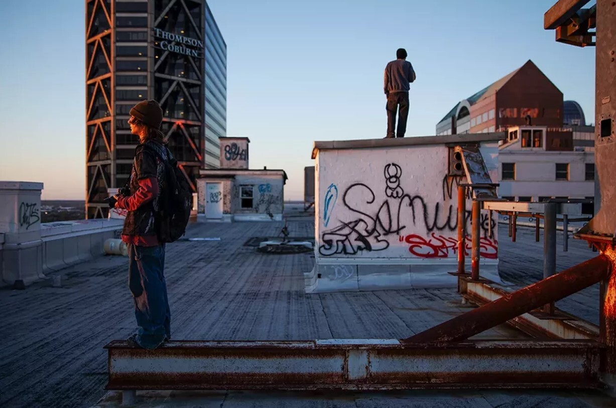 Two urban explorers look out over Downtown St. Louis from the roof
