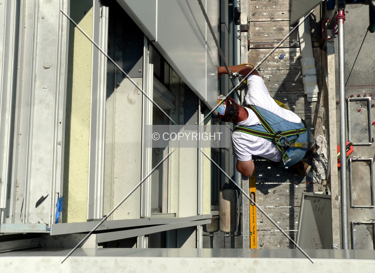 Construction worker installing metal panels for the facade