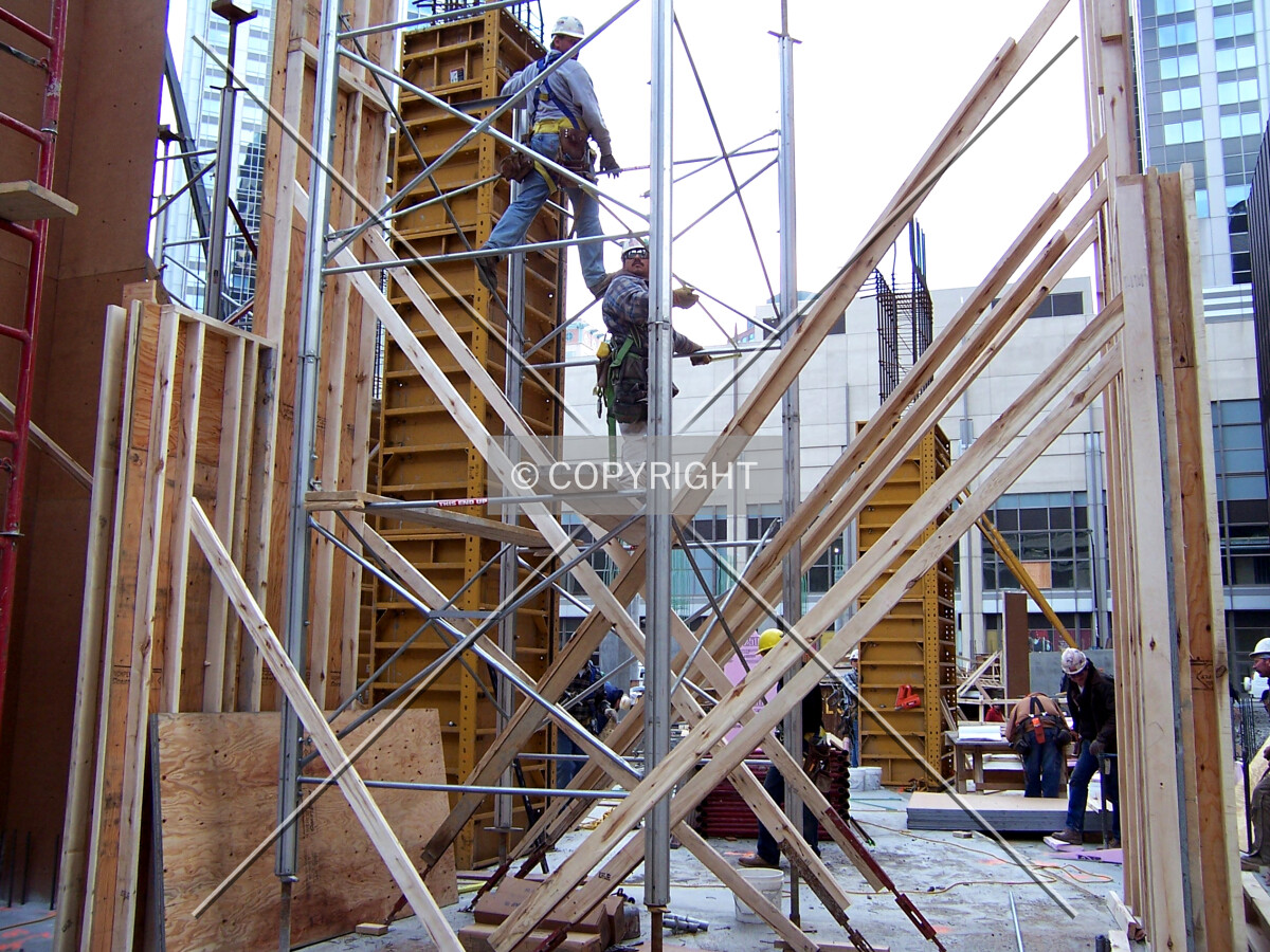 Workers assembling scaffolding to hold up the concrete forms of the second floor slab