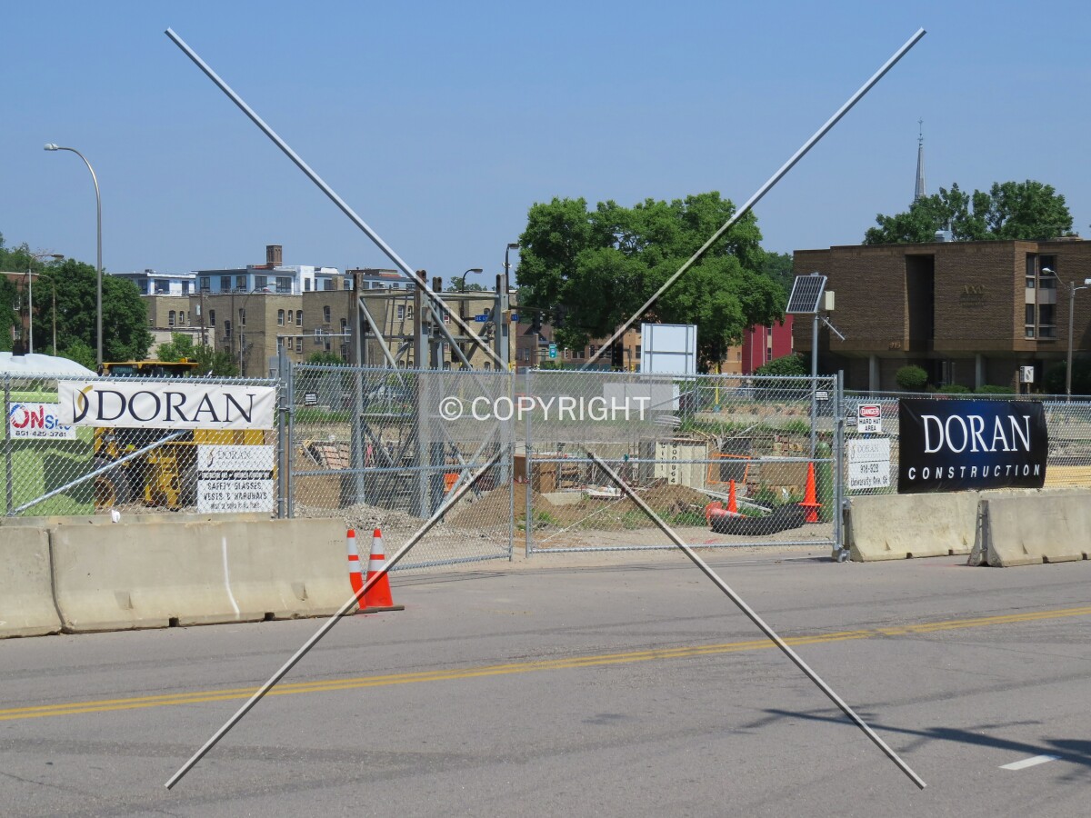 Construction entrance and future tower crane base from across 10th Avenue SE