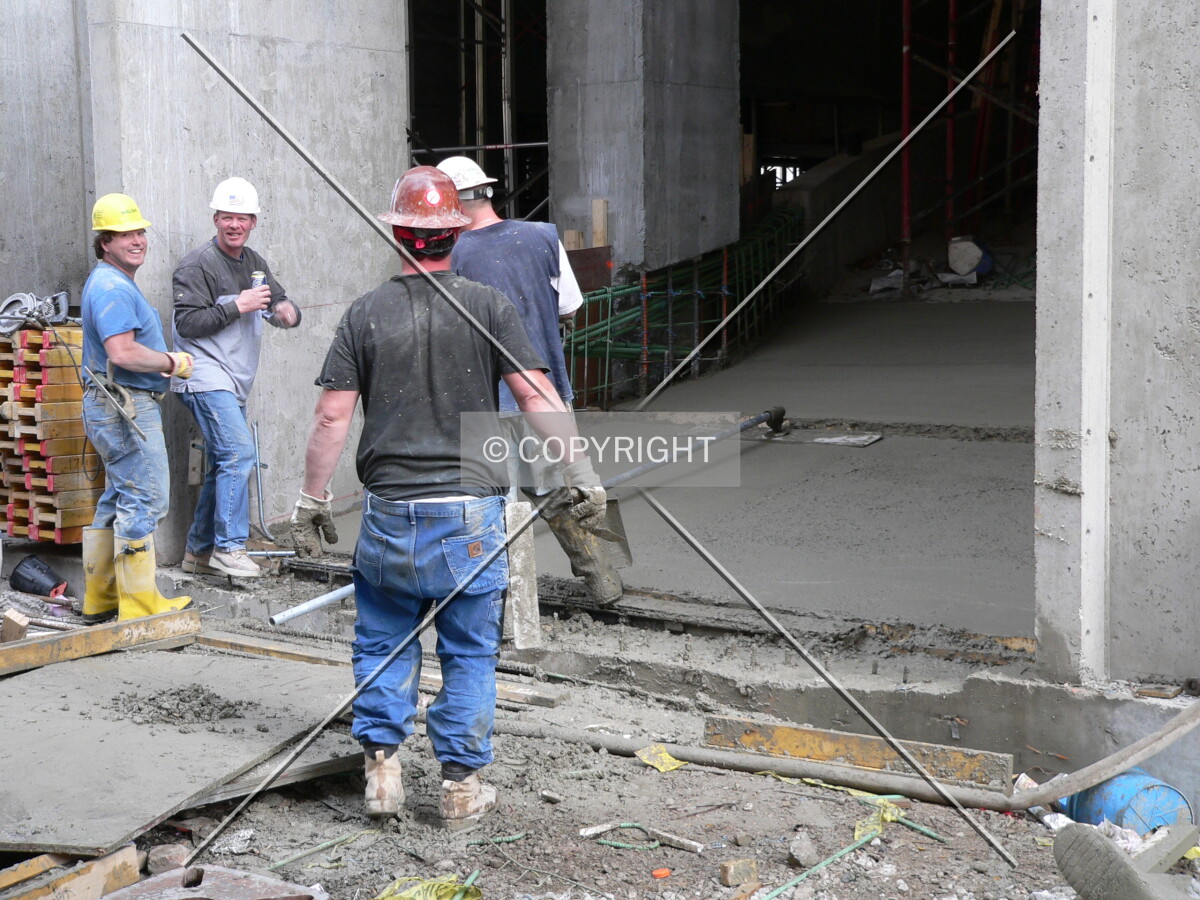 Construction workers smoothing out the concrete on the parking garage ramp