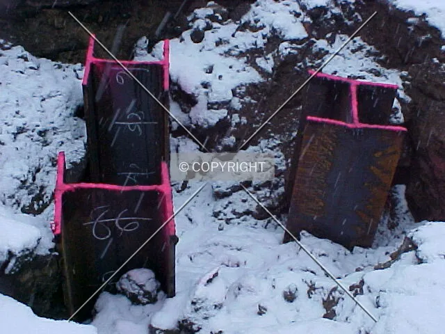 A trio of steel piles with marking showing their depth into the ground