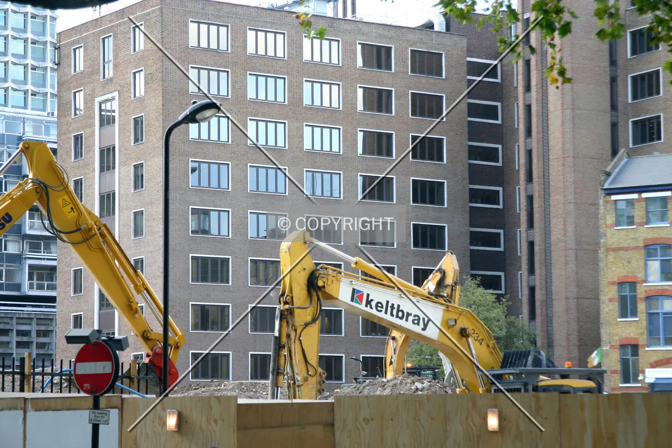 View west of machinery rising over the site hoarding