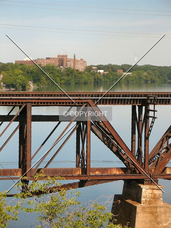 Distant view to the north from the 1st Street/St Germain Street bridge, past an adjacent railroad trestle over the Mississippi River
