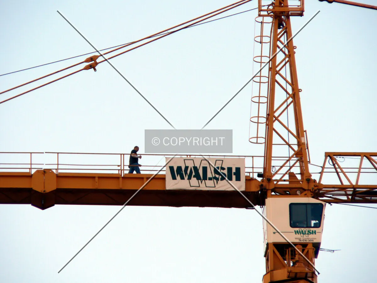 A worker walking along the boom of the tower crane