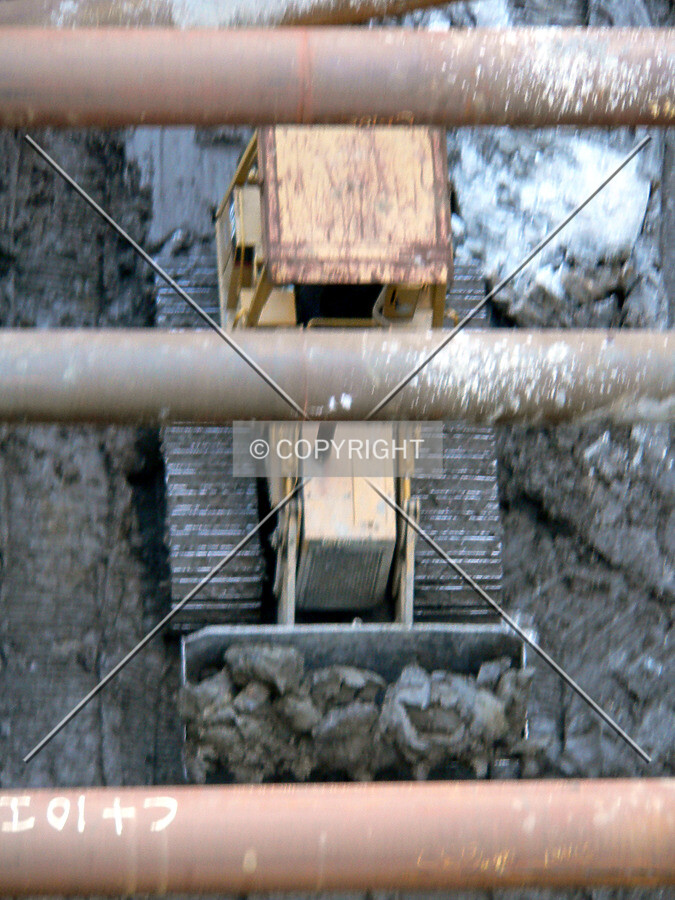 View through raker beams as a buldozer moves around clayduring excavation