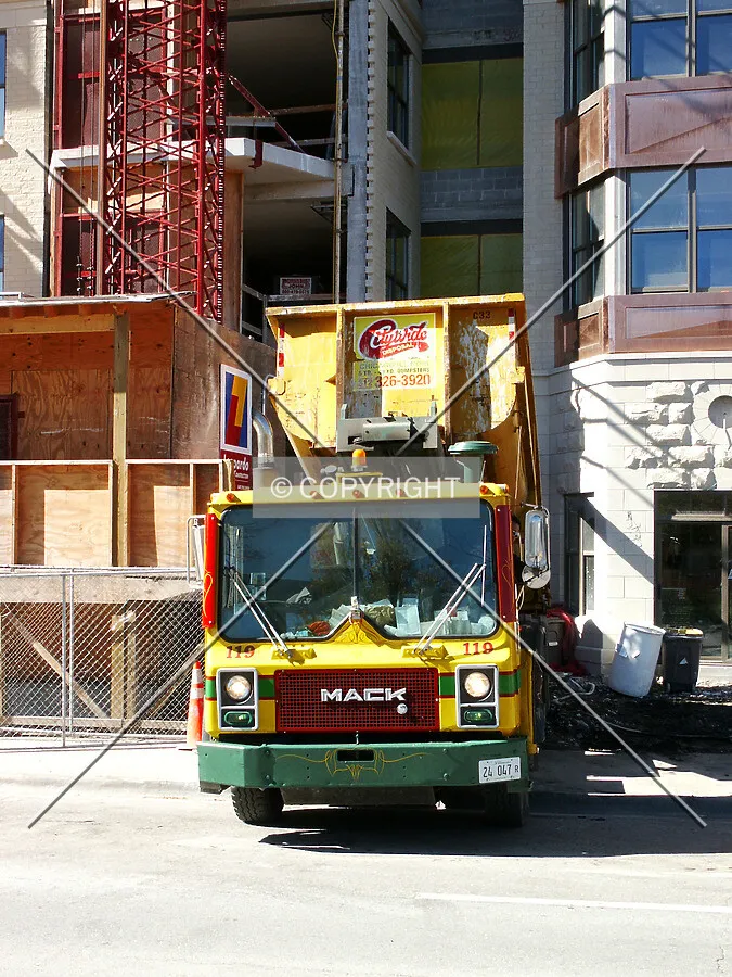 Waste hauler lowering a bin at the edge of the hoist platform
