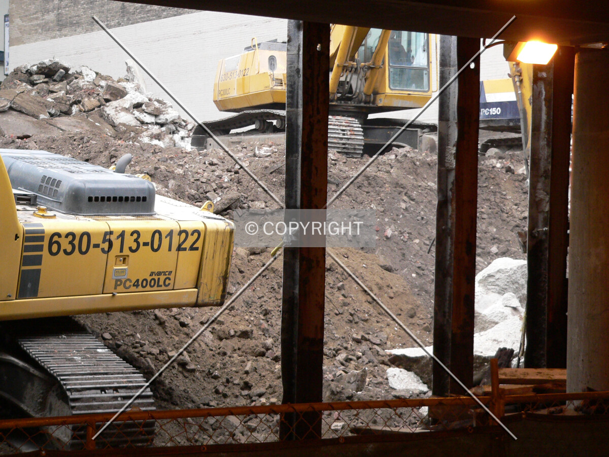 Machinery removing steel and wooden barriers, as well as excavating the site