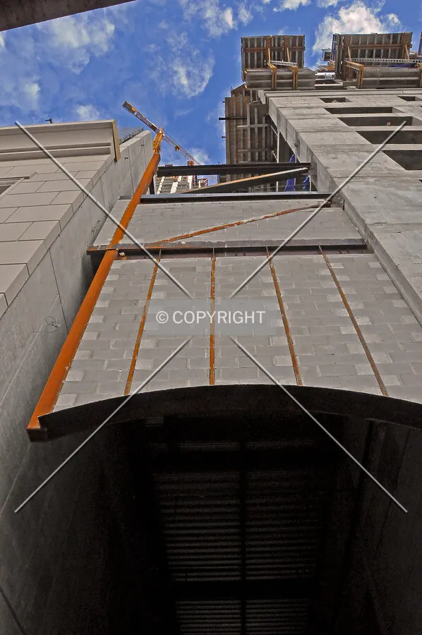 Steel framed cantilever with infill concrete masonry block hanging over an alley to the north of the tower base