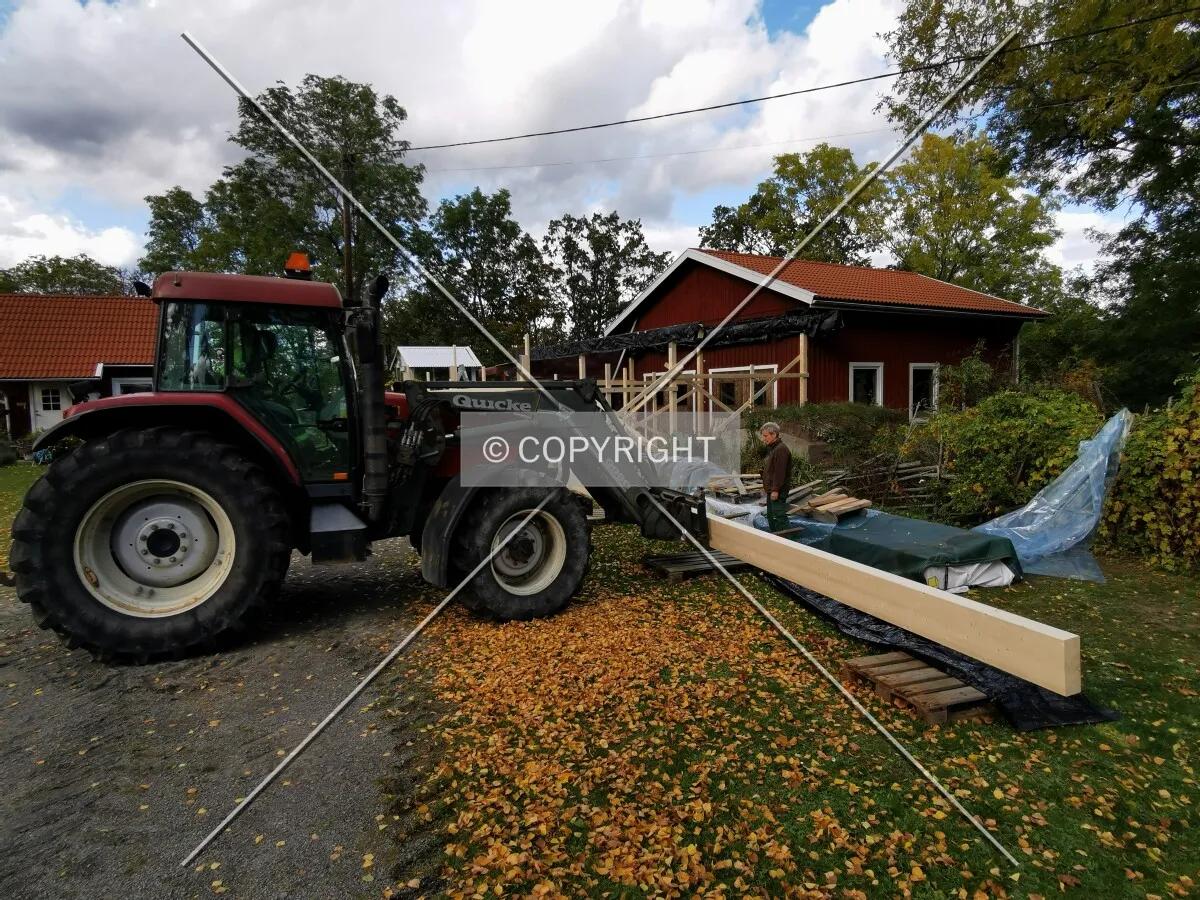 A shed with a wooden framework is constructed using a traktor