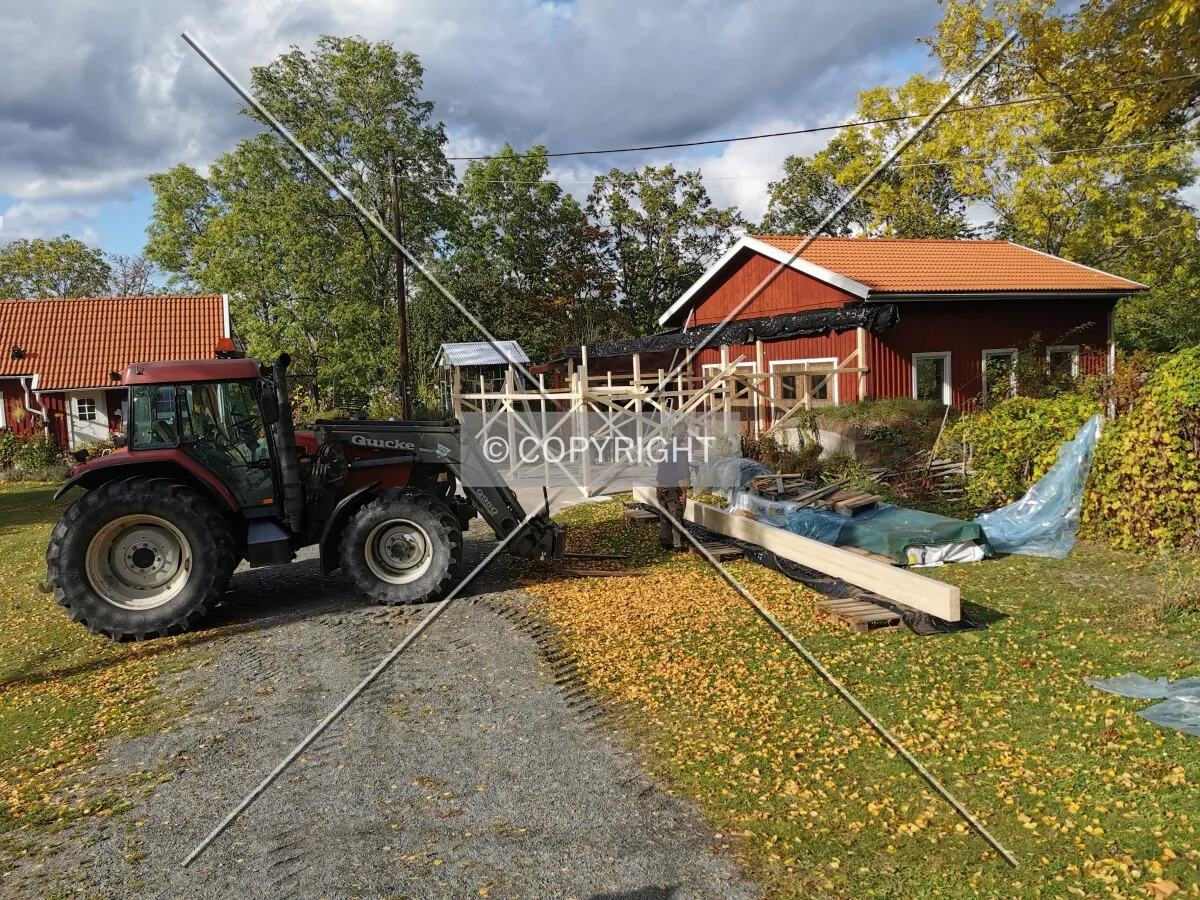 A shed with a wooden framework is constructed using a traktor