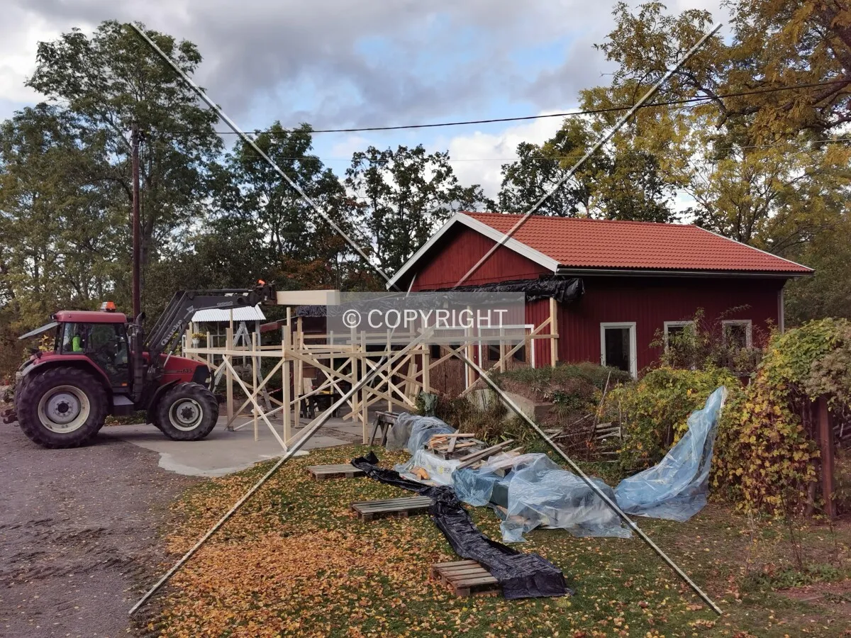 A shed with a wooden framework is constructed using a traktor