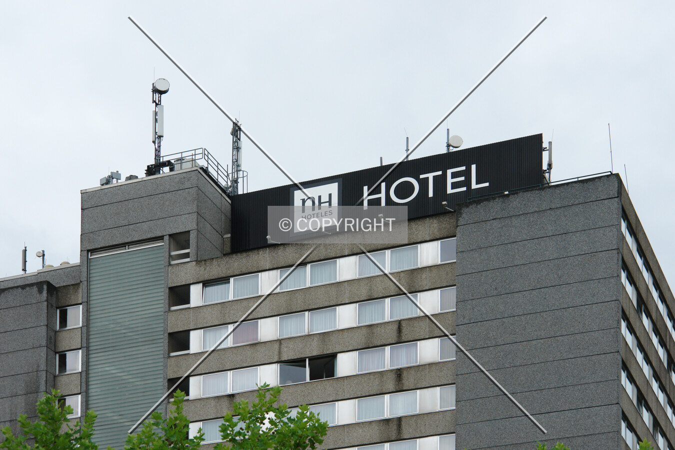 Upper section of the building including the NH Hoteles logo and transmission antennae