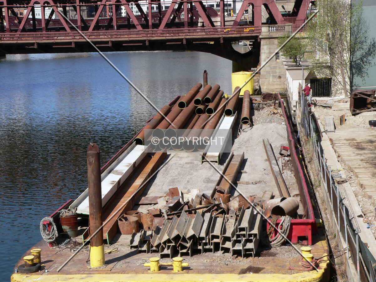 A barge tied up dockside with some construction material on it