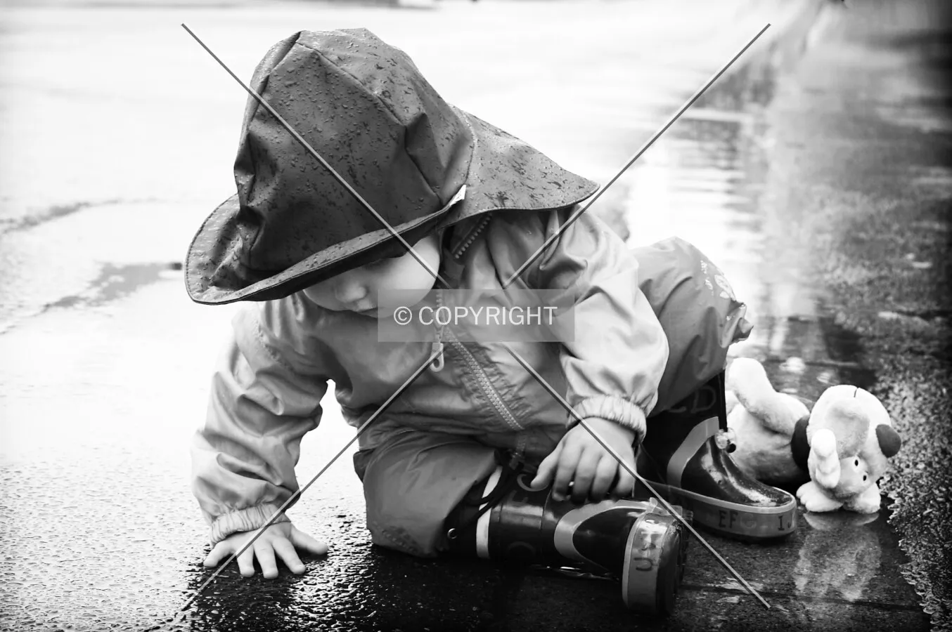 baby sitting in puddle on street