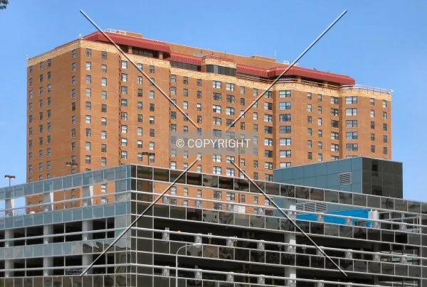 View from the southwest; Upper floors rising over a Mayo Parking Ramp