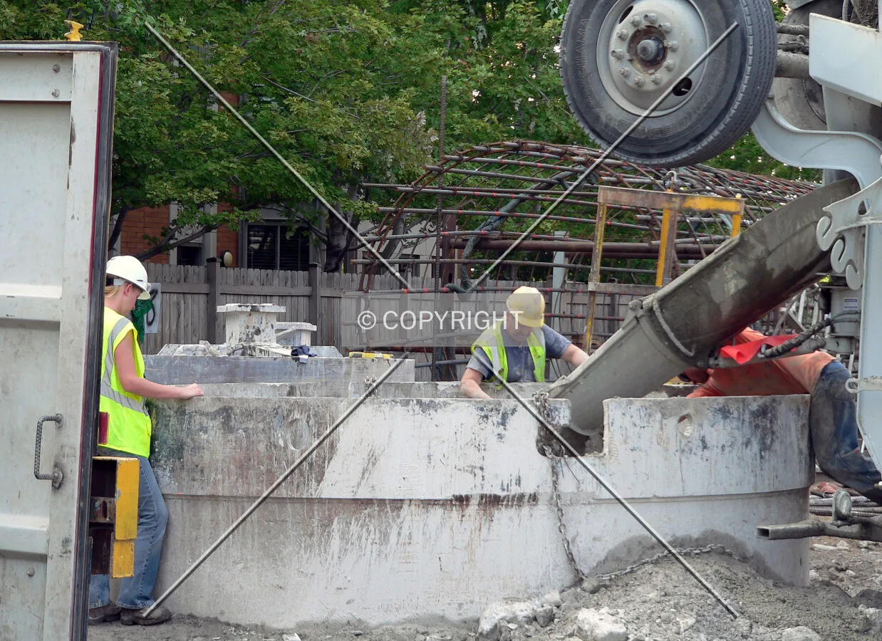 View into the site as concrete is poured down a caisson hole