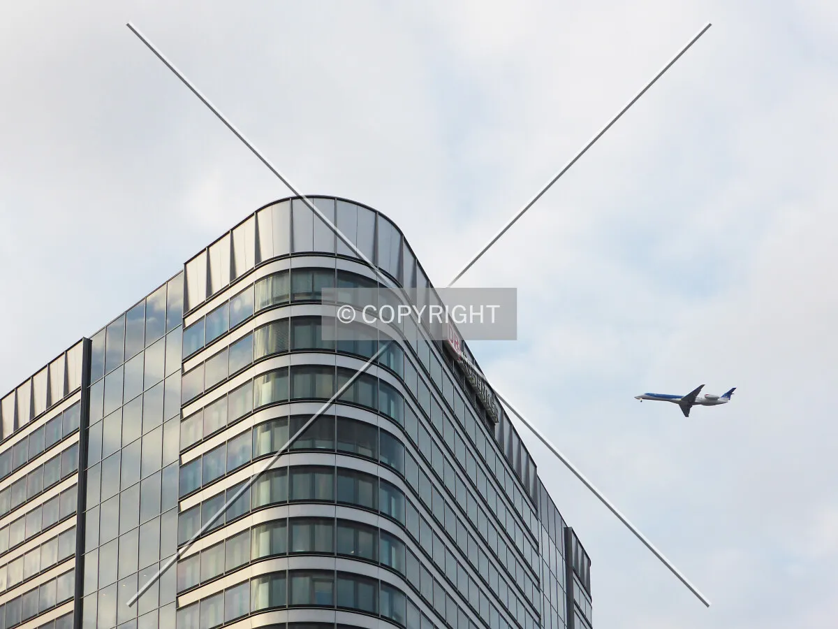 Building in the foreground and flying plane in the background