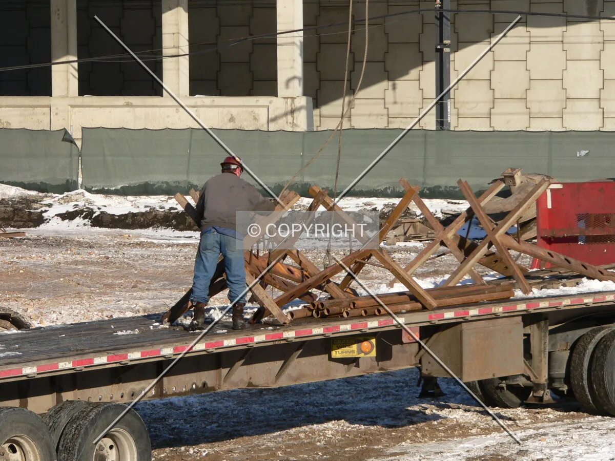 Construction workers unloading stands that will be used to form rebar cages for caisson construction