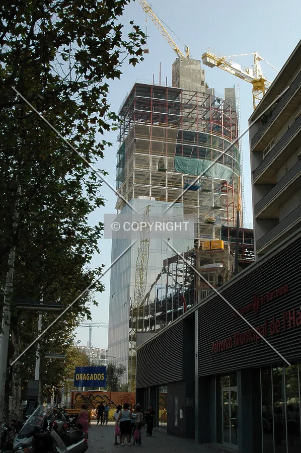 Tower rising between a residential building and street trees