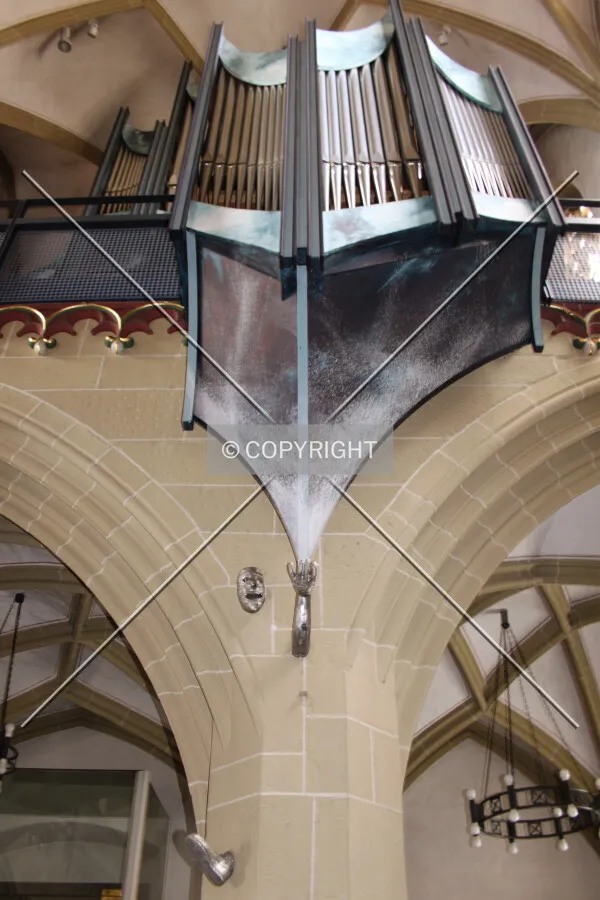 Man encased in a column holding up the pipe organ