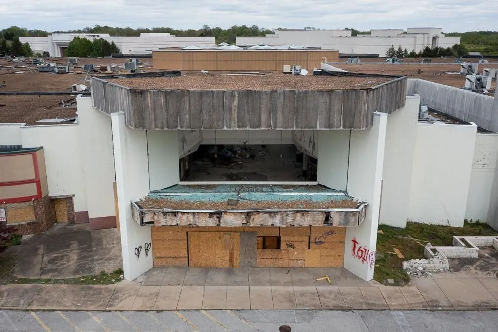 Shattered windows and boarded-up doors frame an entrance; April 22, 2023