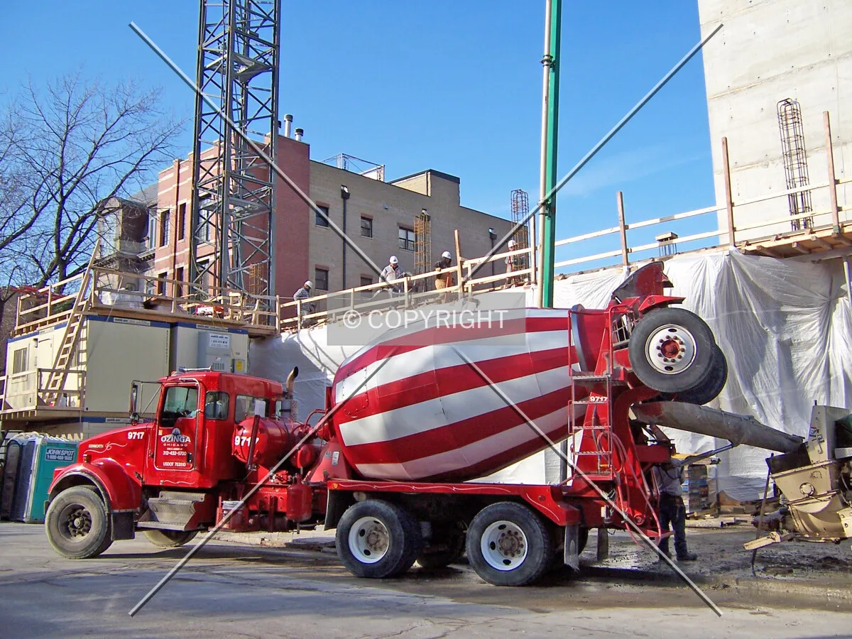 An Ozinga concrete truck dumping concrete into the concrete pump hopper along Grace Street