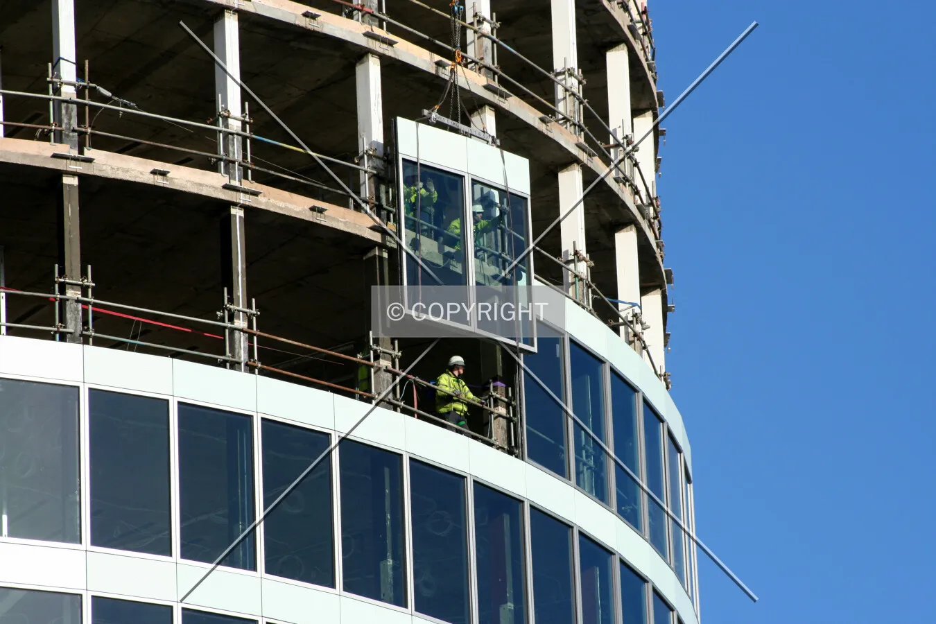 View from the base showing a facade panel being lifted into place