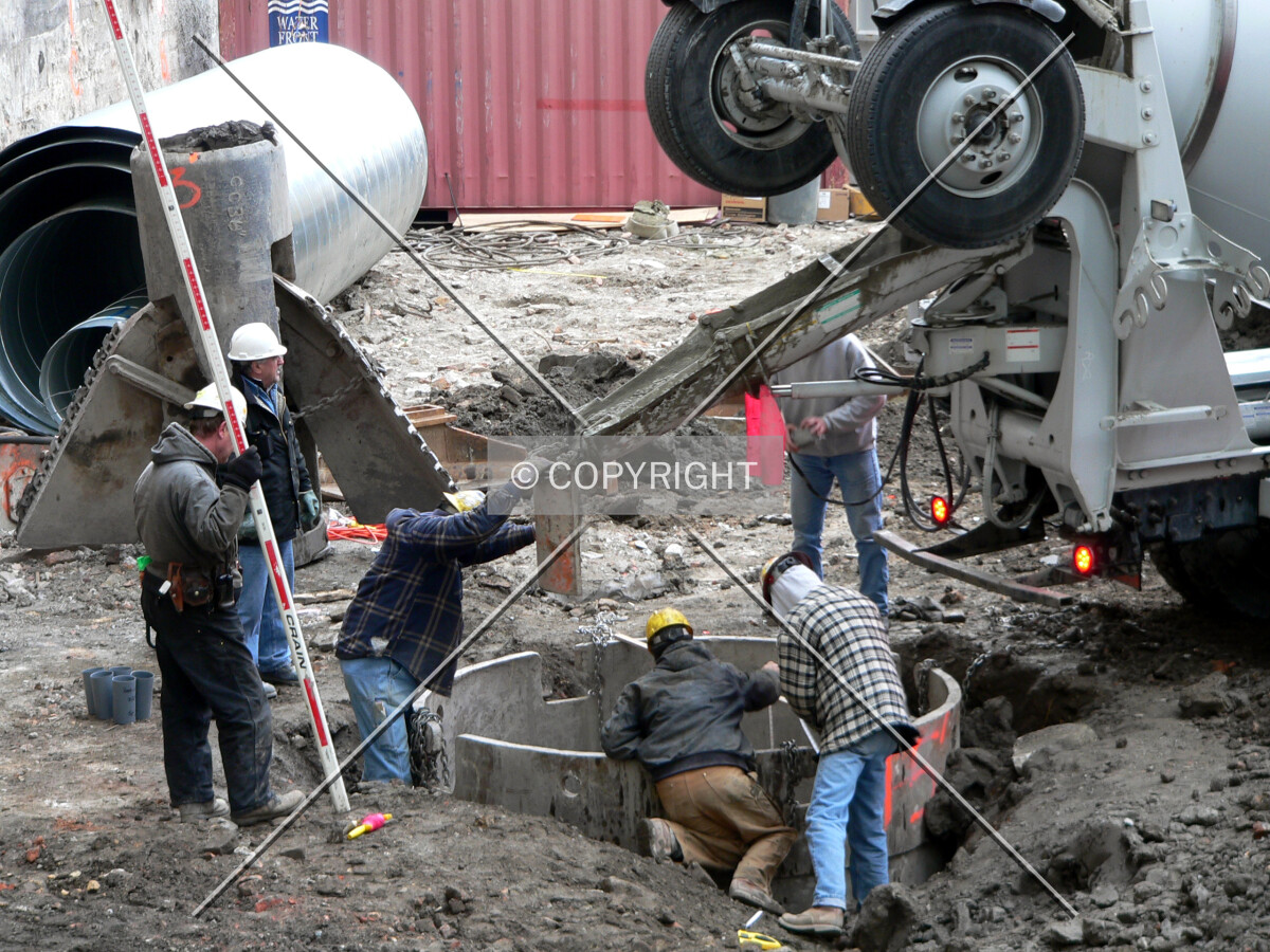 Workers dumping concrete down a caisson hole