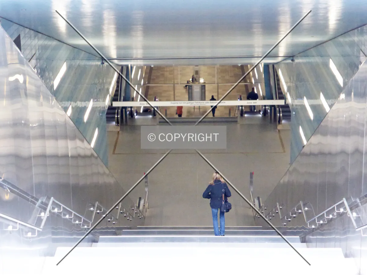 A woman is walking down the stairs of the underground metro station