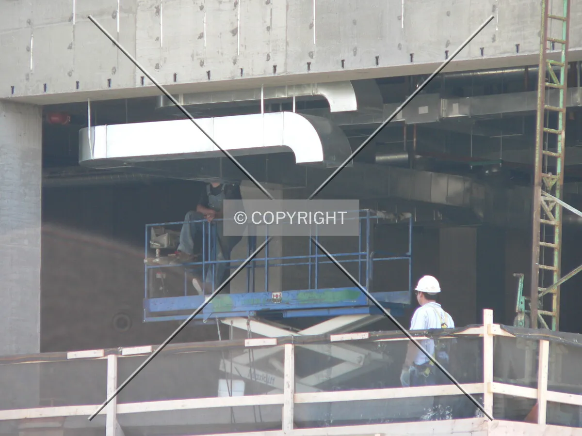 Workers installing duct work within the building