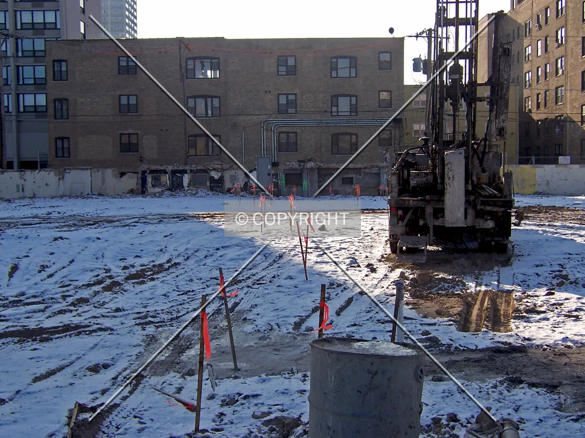 Looking south from Foster Avenue. A soil drilling rig for test samples and caisson marking stakes are present on the site