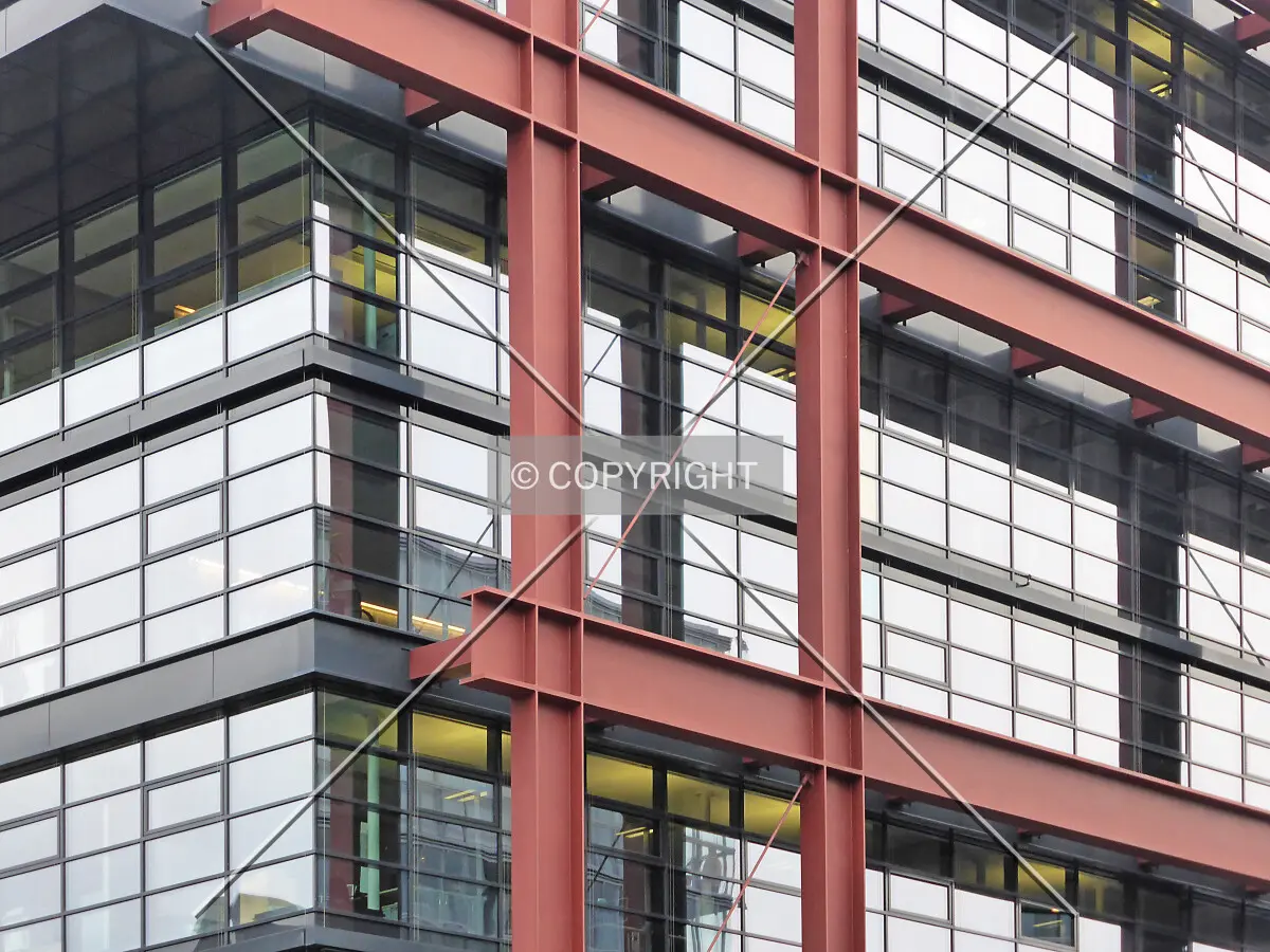 Red steel framework in front of the glass facade