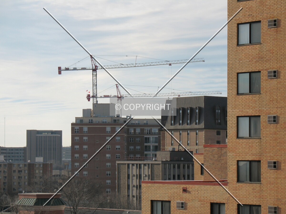 Tower cranes constructing a new tower to join apartment buildings west of downtown