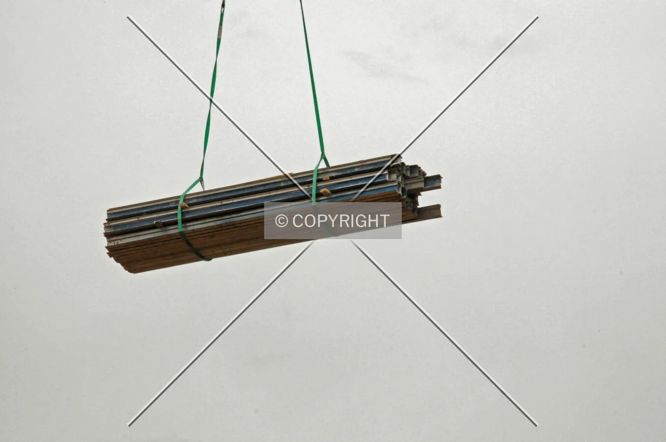 Crane hoisting a bundle of scaffolding beams