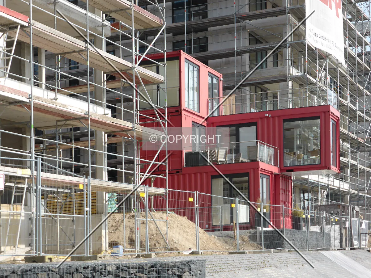A red container building between the construction sites
