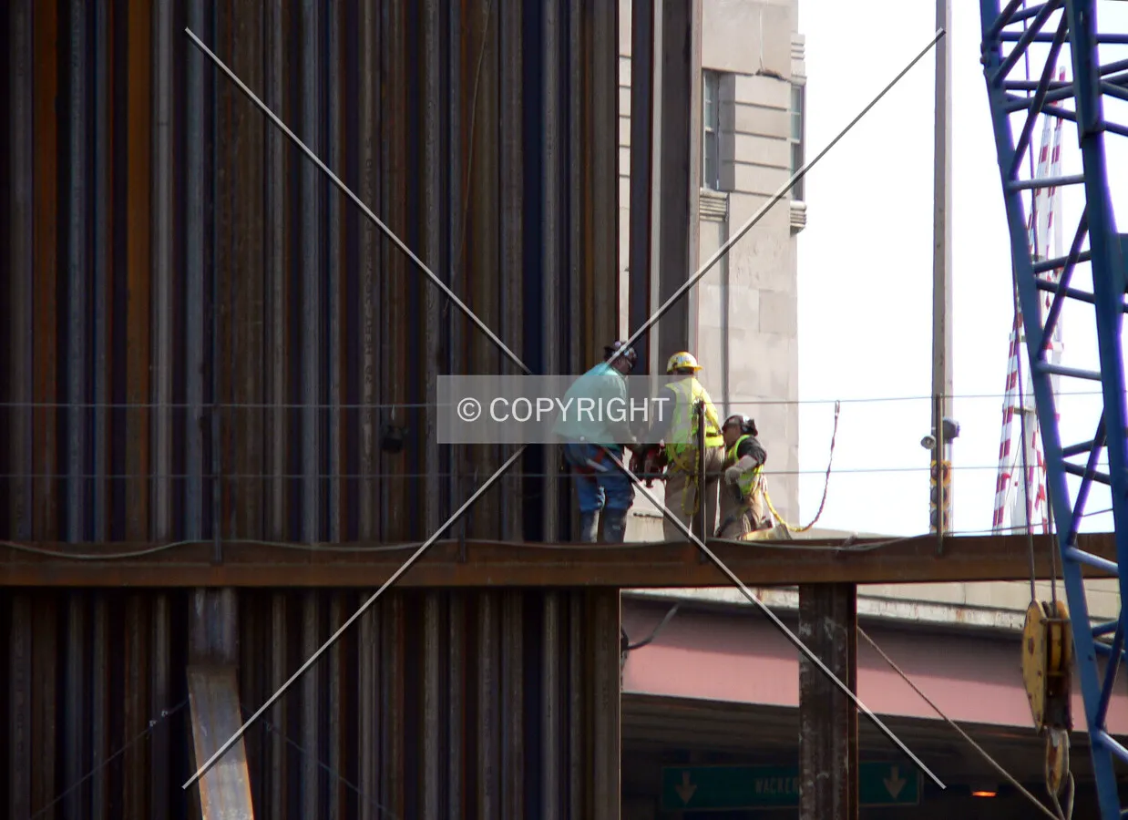 Workers guiding a piece of steel sheeting into place