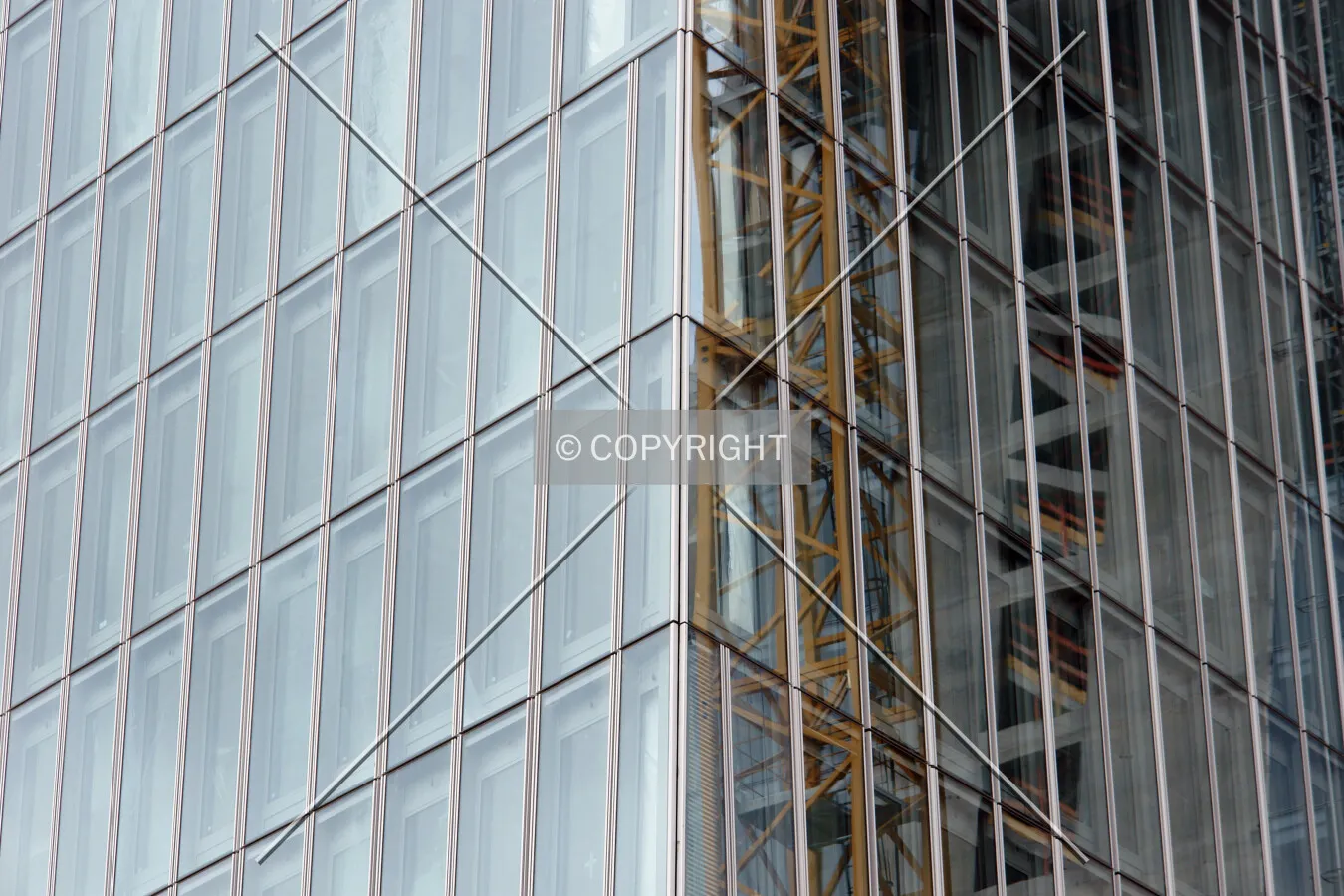 Construction crane is reflecting in the glass facade