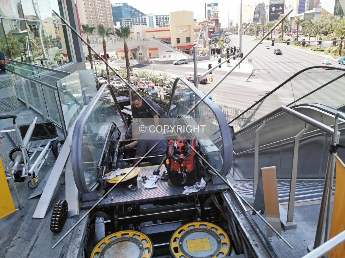 Two men performing escalator maintenance