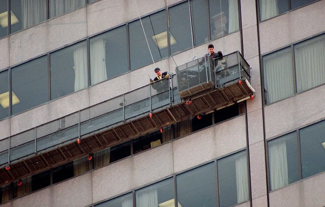 Two window washers from Deddens Window Cleaning look down at all the firefighting equipment that responded to their stuck cable car at the James A. Rhodes State Office Tower, Monday, March 23, 1998