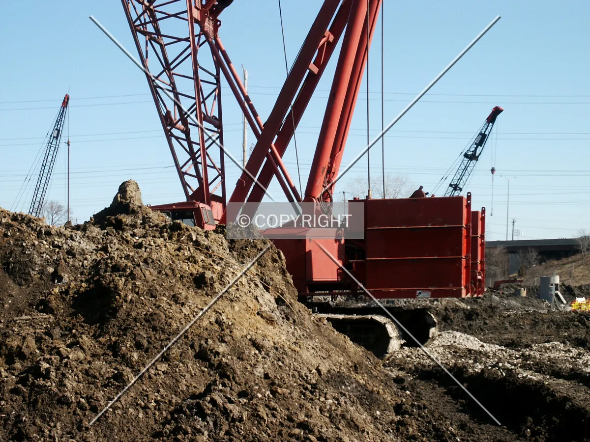 Cranes behind a mound of dirt