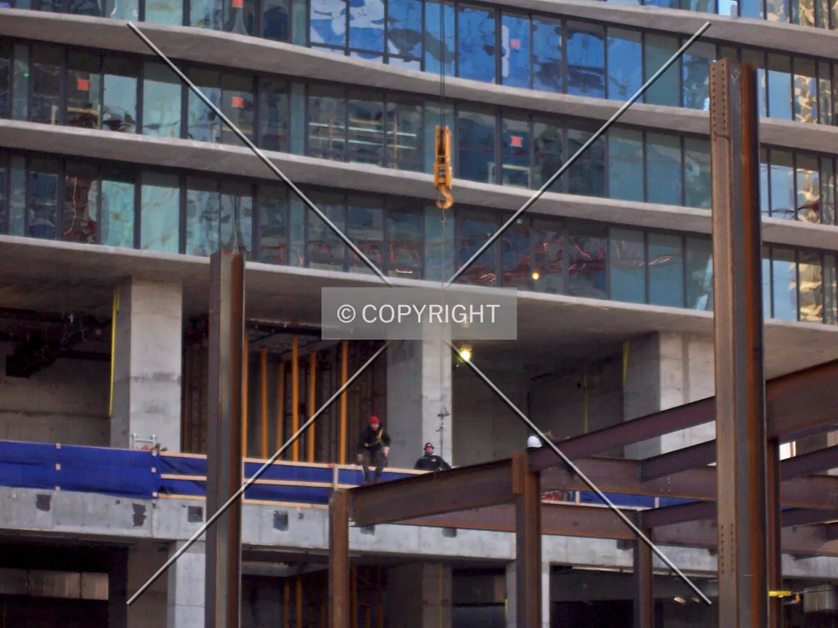Iron workers atop steel beams of the retail podium