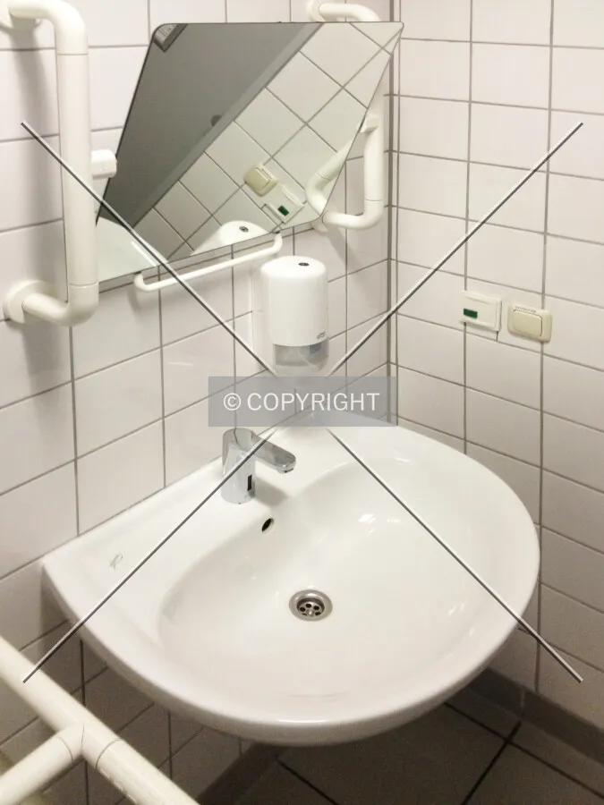 A sink for disabled people featuring a tilted mirror