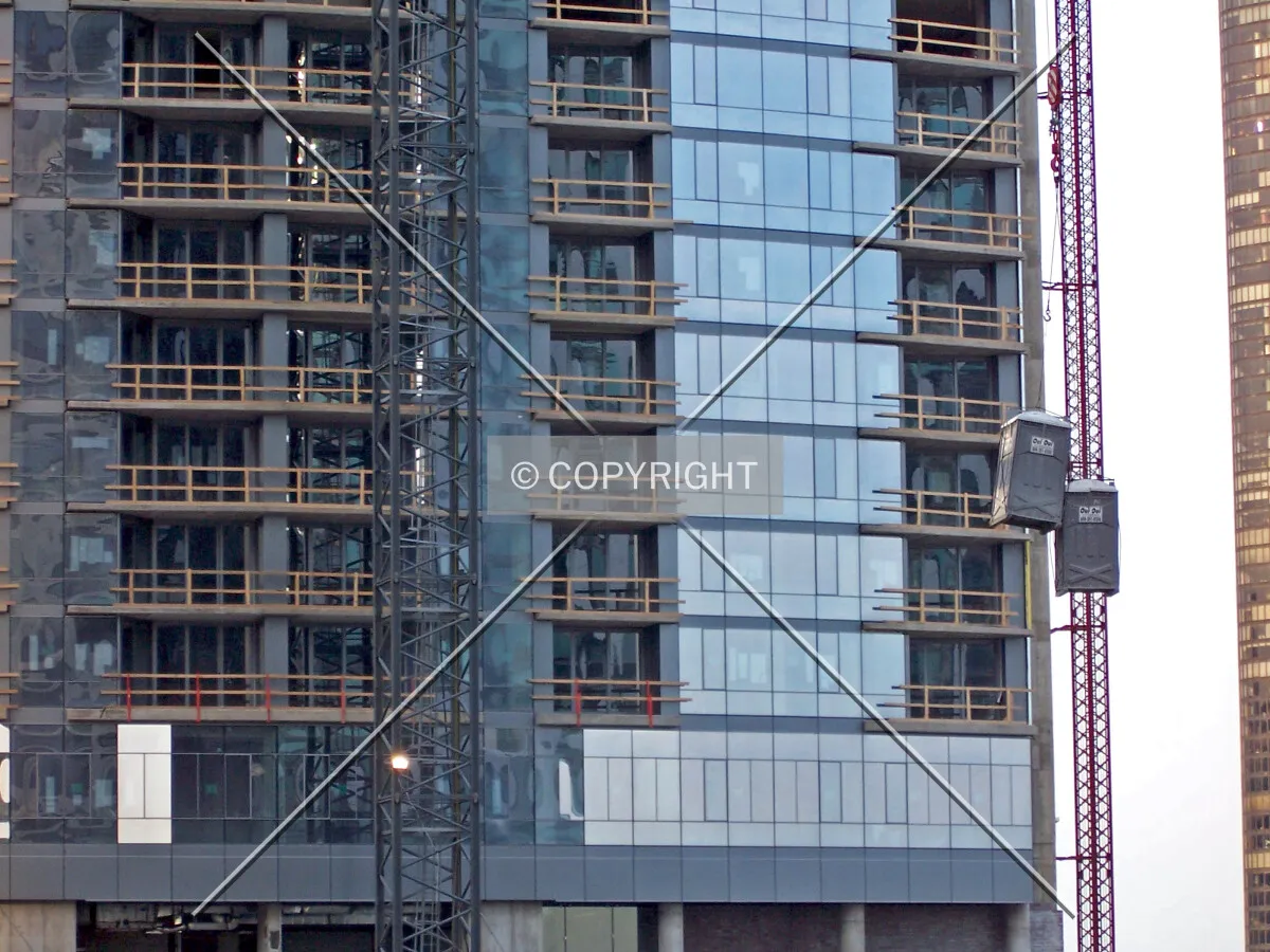 The tower crane lifts portable toilets in front of the south facade
